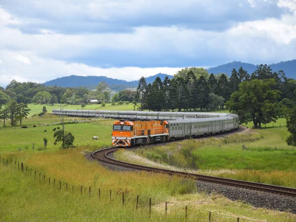 The Great Southern curving through green farmland below forested hills at Nana Glen