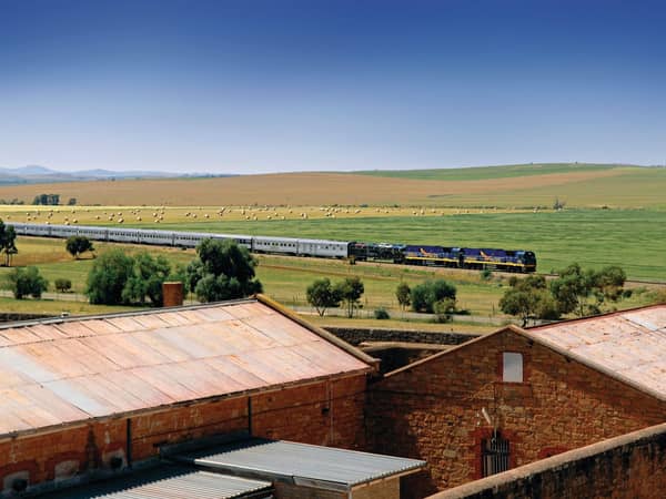 The Indian Pacific passing green farmland and old stone sheds