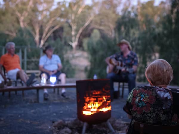 Guests around a riverside campfire with live music on the Murray