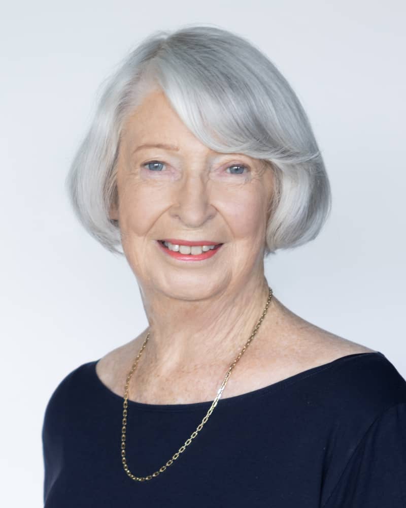 Nancy Crooks, smiling, with silver hair and a navy top