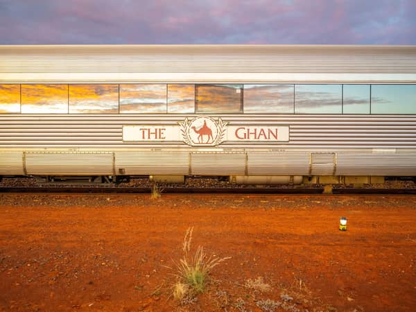A silver Ghan carriage with the sunset reflected in its windows
