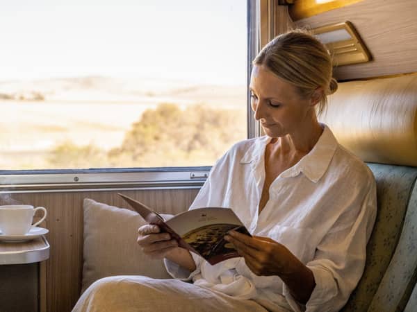 A guest reading in her Gold Service cabin, with the outback outside the window