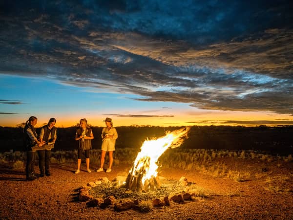 Guests around a campfire at sunrise near Marla, South Australia